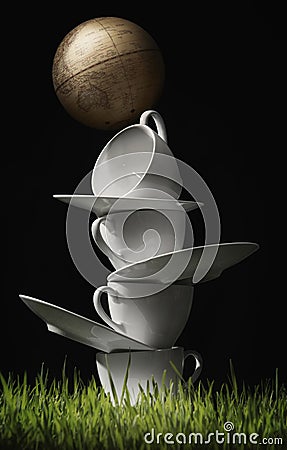 A stack of cups, saucers and a globe. Conceptual image shot Stock Photo