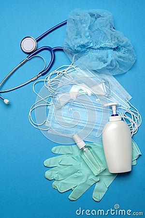Stack of Disposable blue medical face masks, rubber latex gloves, goggles, stethoscope and alcohol hand sanitizer Stock Photo