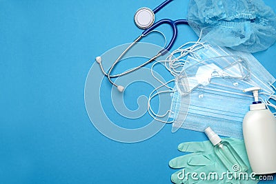 Stack of Disposable blue medical face masks, rubber latex gloves, goggles, stethoscope and alcohol hand sanitizer Stock Photo