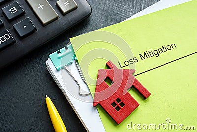 A stack of documents about loss mitigation with a figurine of a house. Stock Photo
