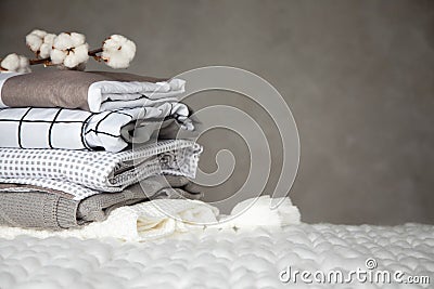 Stack of folded warm blankets with different design patterns and cotton branch on grey background Stock Photo