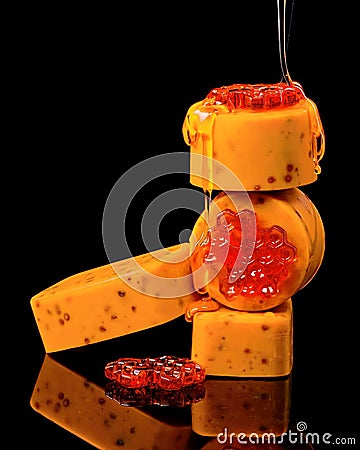 A stack of four rectangular soap bars, some with visible honeycomb designs, are drizzled with honey, creating a luxurious and Stock Photo