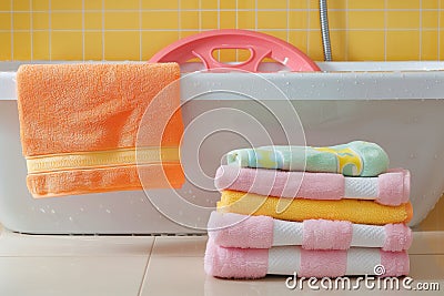 stack of fresh baby towels next to a bath support in the tub Stock Photo