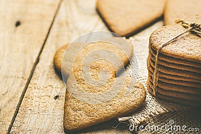 Stack of Ginger Heat Shape Cookies Tied with Twine on Burlap on Weathered Wood Background. Valentine Stock Photo