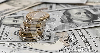 Stack of golden coins on dollar bills on a table Stock Photo