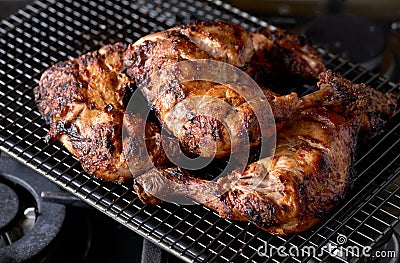 A stack of grilled tandoori spiced chicken legs on a wire rack Stock Photo