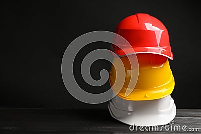 Stack of hard hats and space for text on black background. Stock Photo