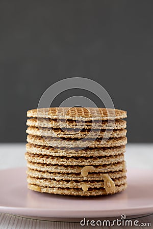 Stack of homemade Dutch stroopwafels with honey-caramel filling on pink plate, side view. Close-up Stock Photo