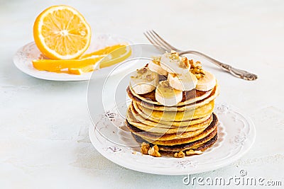 Stack of homemade pancakes with banana, maple syrup and walnuts on vintage plate. Stock Photo