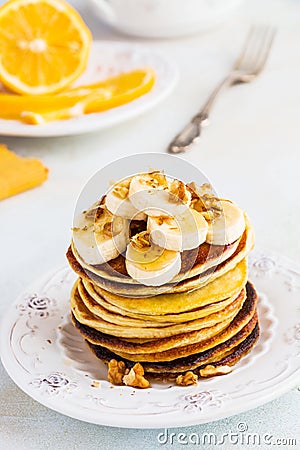 Stack of homemade pancakes with banana, maple syrup and walnuts on vintage plate. Stock Photo