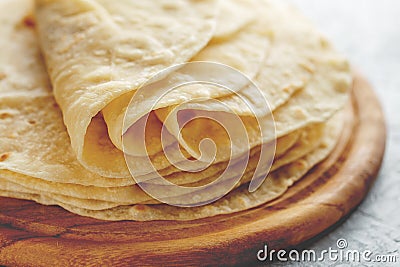 Stack of homemade wheat flour tortilla wraps on wooden cutting board. Stock Photo