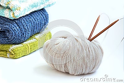 Stack of knitted sweaters and knitting needles with a ball of yarn. Home comfort. Casual wear Stock Photo