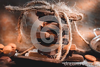 Stack of milk and dark chocolate pieces tied together with twine and bow atmospheric front view photo. Stock Photo