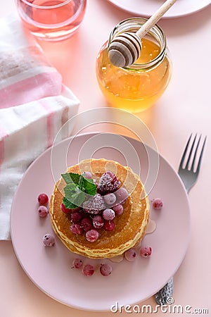 Stack of pancakes with frozen raspberry, red currant and honey on pink background. Selective focus Stock Photo