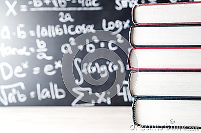 Stack and pile of books in front of a blackboard in school. Stock Photo