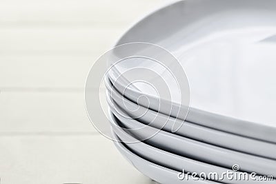 Stack pile of rectangular white ceramic dishes with rounded edges on wooden white background Stock Photo
