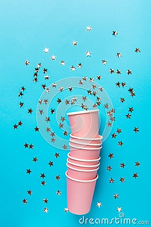 Stack of pink drinking paper cups on mint blue background glittering star shape confetti. Birthday party celebration holiday kids Stock Photo