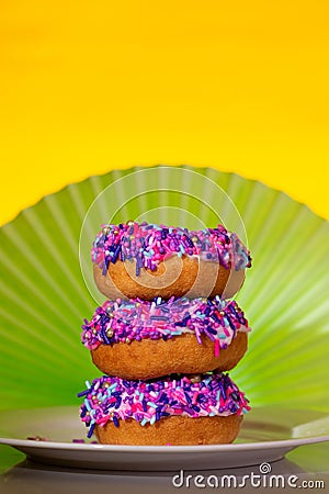 A stack of 3 pink sprinkle donuts, art nouveau style background Stock Photo