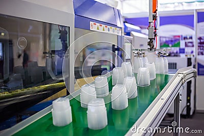 Stack of food containers on conveyor belt of plastic injection molding machine Stock Photo