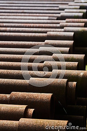 Stack of rusty brown hollow iron pipes for drilling for oil, natural gas or groundwater Stock Photo