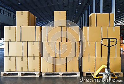 Stack of shipment package boxes on wooden pallets and hand pallet truck in interior warehouse storage. Stock Photo