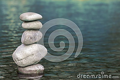Stack of stones balancing on top in blue water of the river Stock Photo