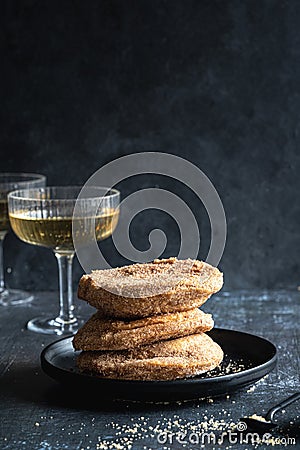 A stack of three apple beignets (apple fritters) on black background with glass of champagne Stock Photo