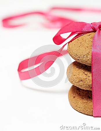 Stack three oatmeal homemade traditional tasty cookies with pink ribbon and bow as gift macro vertical Stock Photo