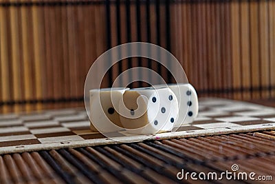 Stack of three white plastic dices on brown wooden board background. Six sides cube with black dots. Random number Stock Photo