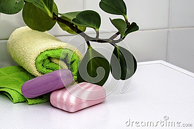 a stack of towels bars of soap and a houseplant on the bathroom table Stock Photo