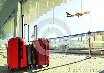 stack of traveling luggage in airport terminal and passenger plane flying over sky Stock Photo