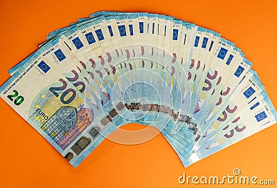 A stack of used blue 20 euro banknotes isolated on a vivid orange background. Stock Photo