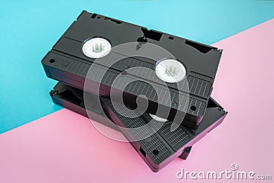 Stack of 3 VHS tapes on pink and blue background. Stock Photo