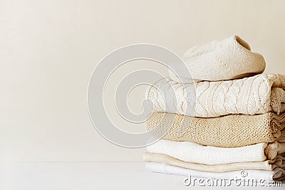A stack of warm beige knit sweaters. Stock Photo
