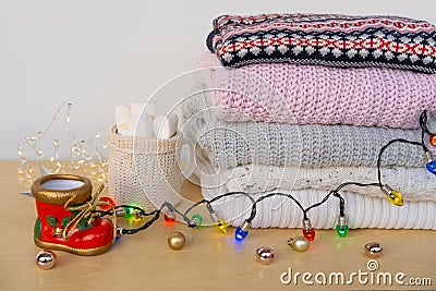 stack warm woolen sweaters, cocoa with marshmallows, colorful Christmas garlands, Christmas atmosphere and coziness at home, Stock Photo