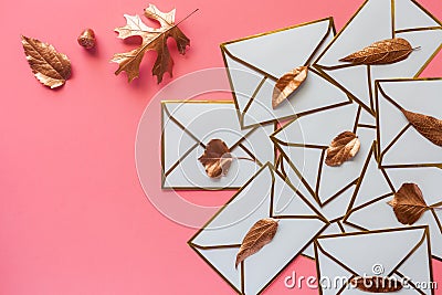 Stack of white envelopes with golden leaves on blush pink background with copy space Stock Photo