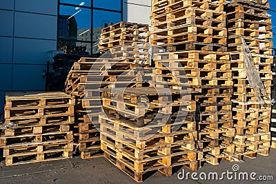 A stack of wooden pallets in an internal warehouse. An outdoor pallet storage area under the roof next to the store. Piles of Euro Stock Photo