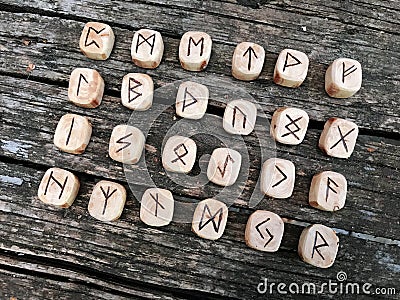 A stack of wooden runes at forest. Wooden runes lie on a old wood background. Runes are cut from wooden blocks. On each Stock Photo