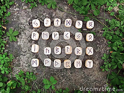 A stack of wooden runes at forest. Wooden runes lie on a rock background in the green grass. Runes are cut from wooden Stock Photo
