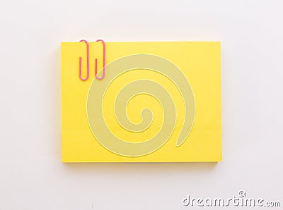 Stack of yellow sheets of paper with pink paper clip on a white Stock Photo