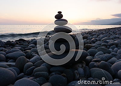 Stack of zen stones on the beach at sunset, beautiful seascape. Made of stone tower as rest balance vacation concept. Stock Photo