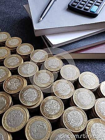 stacked books, calculator, pen and mexican coins of ten pesos Stock Photo