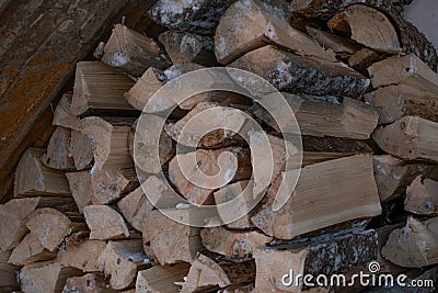 stacked chopped firewood under the stairs. Village life, fireplace or stove for heating. Stock Photo