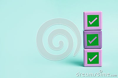 Stacked cubes with check marks on turquoise background. Space for text Stock Photo