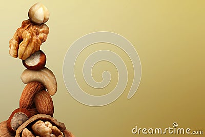 Stacked different nuts on golden gradient background, space for text Stock Photo
