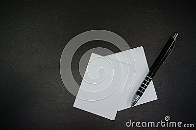 Stacked paper of blank white business cards simulated with an elegant black pen on a black background. Stock Photo