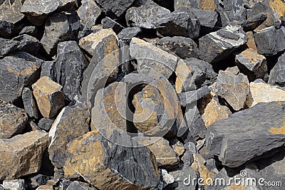 Stacked stone slabs at a stonepit - rocks with irregular flat shape, yellow and gray colored, crushed in a quarry Stock Photo