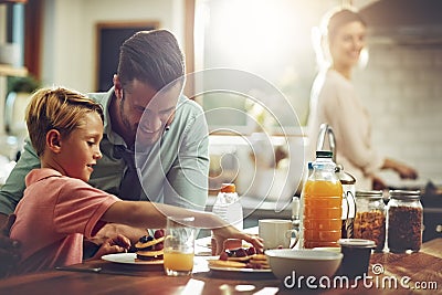 Stacking up the good stuff. a man sitting with his son while hes having breakfast. Stock Photo