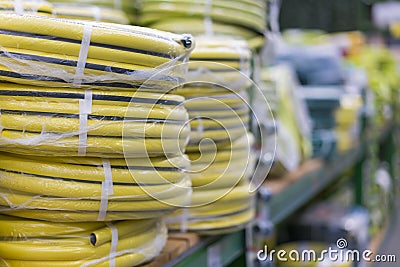 stacks of rolls yellow pvc plastic pipe on the counter in the store. Sale Hoses in the garden of various manufacturers, on shelves Stock Photo