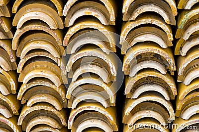 Stacks of yellow ceramic glazed curved roof tiles in a symmetrical pattern Stock Photo